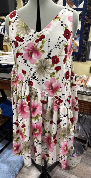 A sleeveless pink and red floral dress on a dress form.