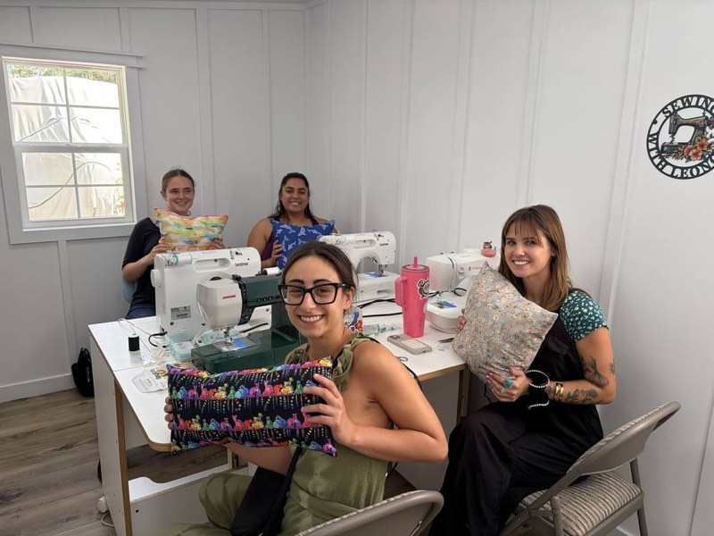 A group of friends sewing together at the studio work table.