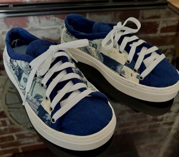 A pair of sneakers covered in blue and white patchwork fabric.